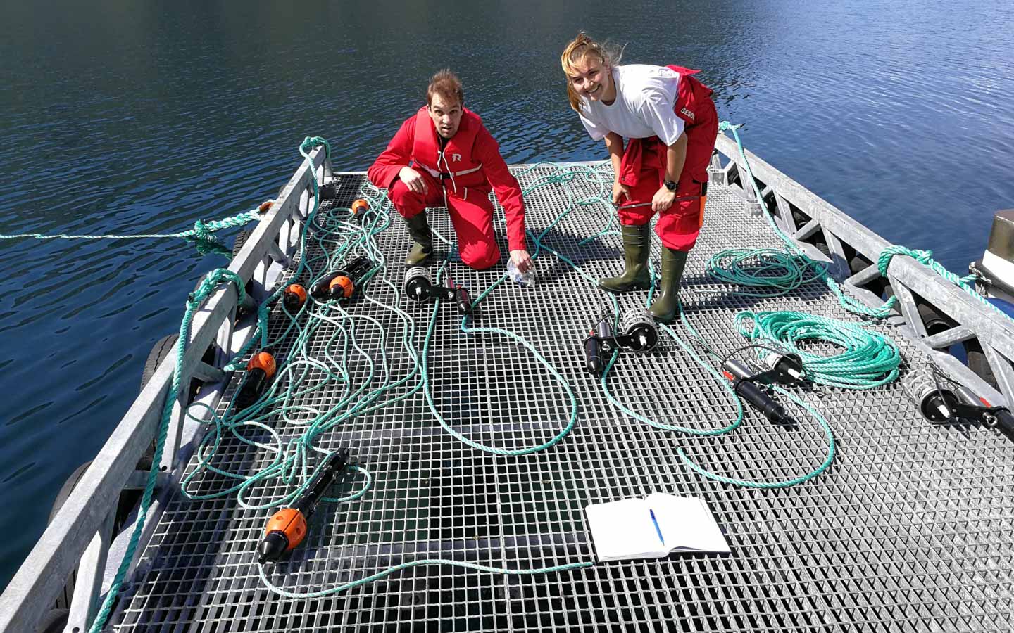 Two people on a dock showing their Innovasea aquaMeasure sensors