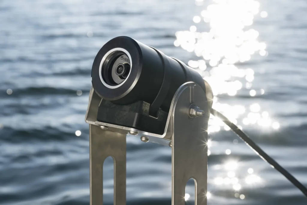 aquaeyes waterproof camera mounted on metal bracket with cable, positioned near sparkling water surface.