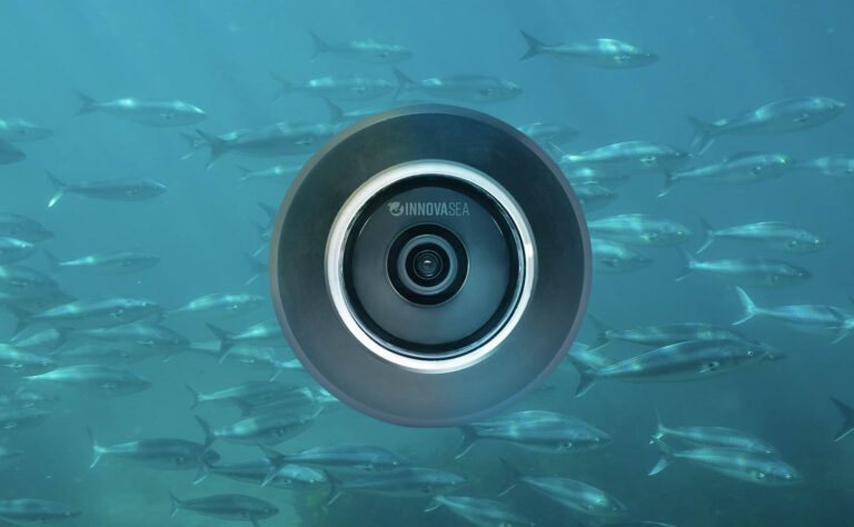 aquaEyes underwater camera device surrounded by a school of fish in blue ocean water.