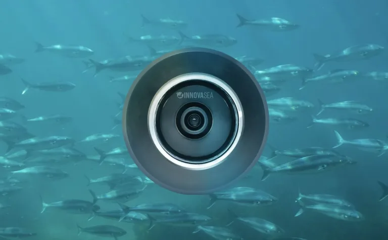 aquaEyes underwater camera device surrounded by a school of fish in blue ocean water.