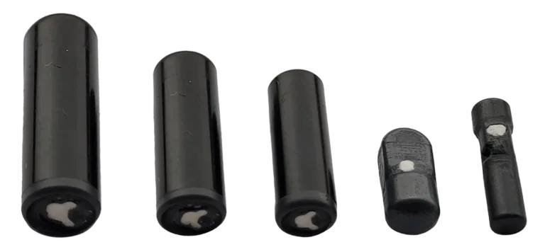 Five black cylindrical predation transmitters of decreasing size arranged in a row, with white circular markings or holes visible on their surfaces.